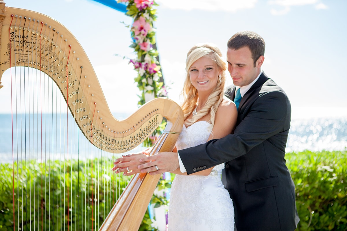 Bride and groom posing beside a golden harp after their wedding at Paradise Cove